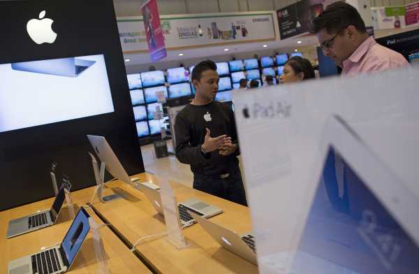 An Apple salesperson speaks to customers at an electronics store in Mumbai