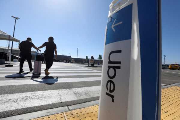 Passengers walk near Uber signage after arriving at Los Angeles International Airport (LAX) in Los Angeles